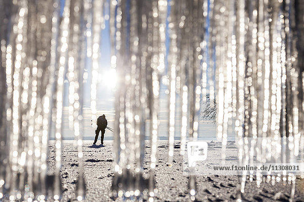 Silhouette of person on beach. icicles on foreground
