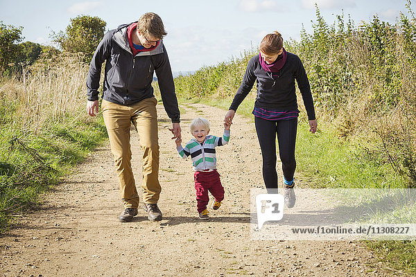 Parents and a child walking along a footpath in the countryside.