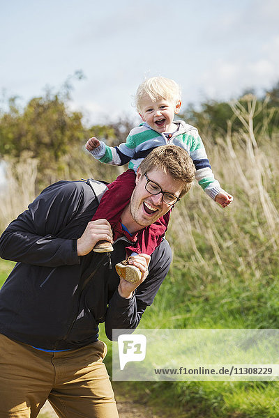 Ein Mann und ein kleiner Junge auf einem Spaziergang  ein Vater  der seinem Sohn ein Huckepack gibt.