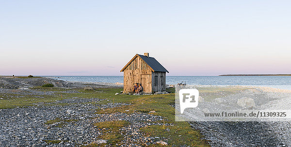 Paar in der Nähe eines Holzhauses an der Küste