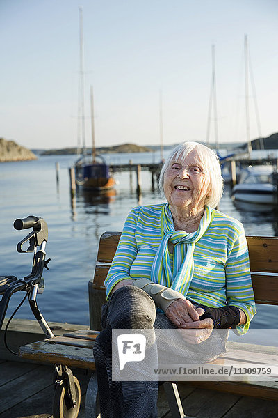 Lächelnde ältere Frau am Meer sitzend