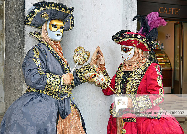 VENEDIG  ITALIEN - Zwei kostümierte Damen fassen sich beim Karneval von Venedig 2015 an den Händen: