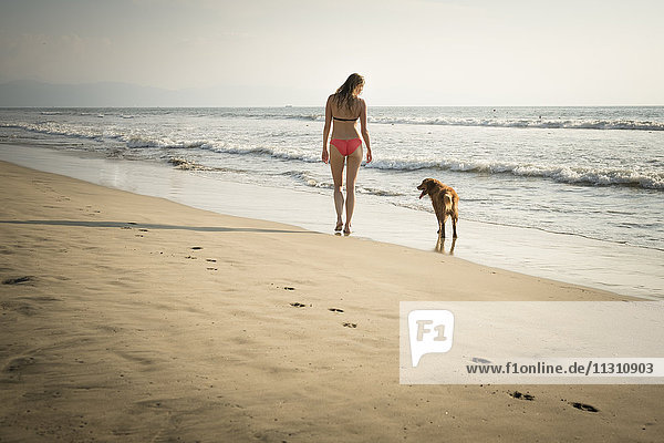 Mexico  Riviera Nayarit  Woman walking with dog at the beach