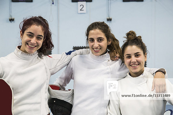 Portrait of three smiling female fencers
