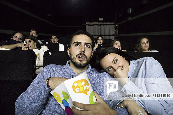 Scared couple watching a movie in a cinema
