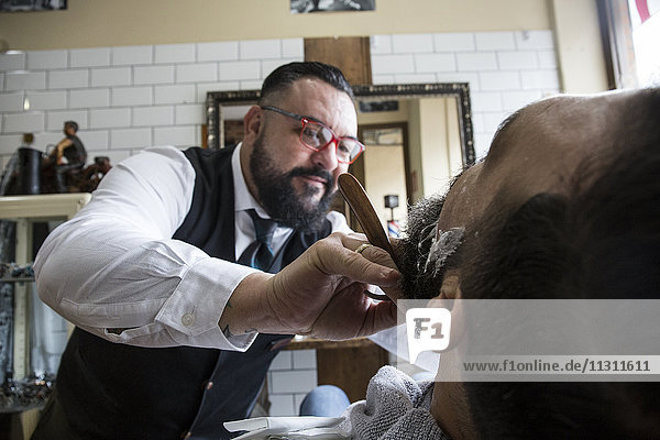 Barber shaving a man using a straight razor