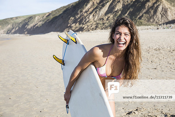 Glückliche Frau mit Surfbrett am Strand