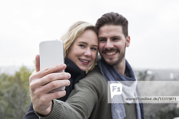 Lächelndes Paar mit einem Selfie im Freien