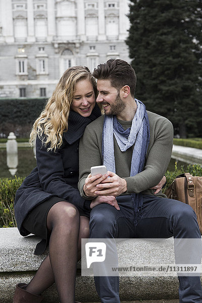 Spanien  Madrid  glückliches Paar mit Handy mit dem Königspalast im Hintergrund