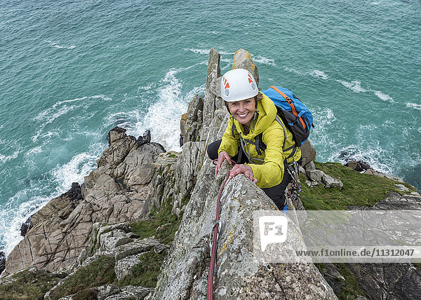 UK  Cornwall  smiling woman climbing on Commando Ridge