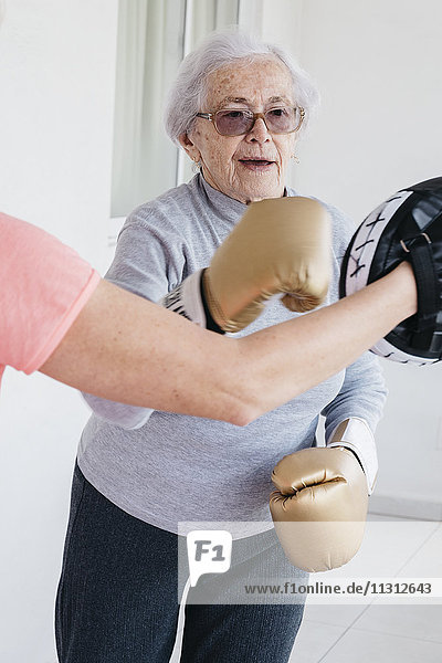 Ältere Frau beim Boxen mit Fitnesstrainerin
