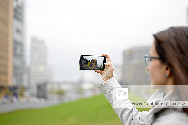 Deutschland  Berlin  Frau beim Fotografieren mit Handy am Potsdamer Platz