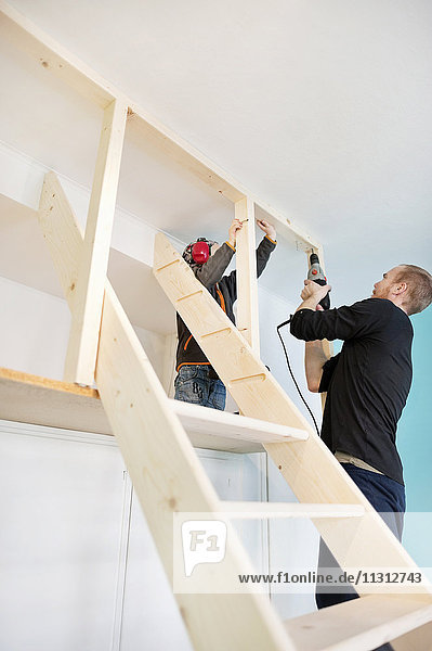 Father and daughter using drill at home
