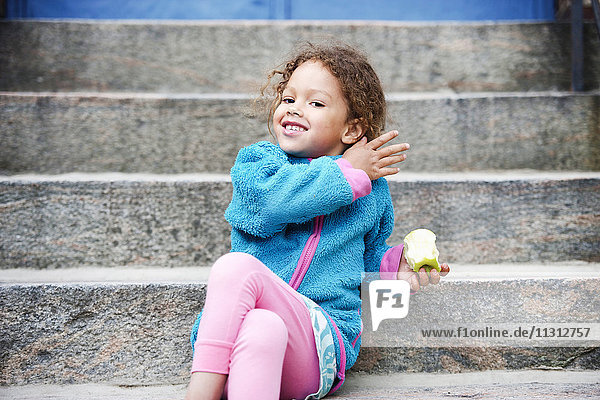 Girl sitting on steps and eating apple