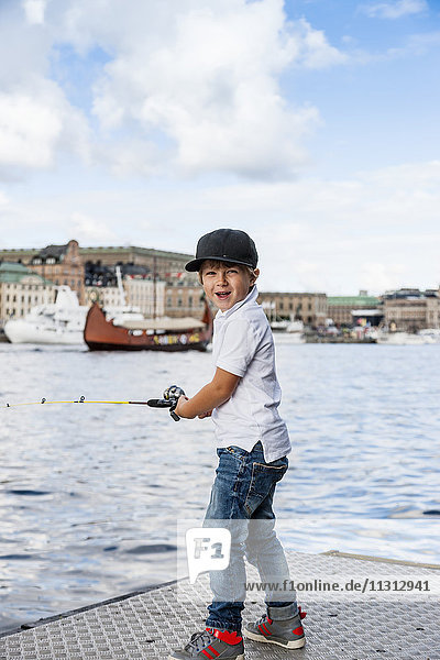 Porträt eines Jungen beim Angeln im Fluss  im Hintergrund die alte Stadt