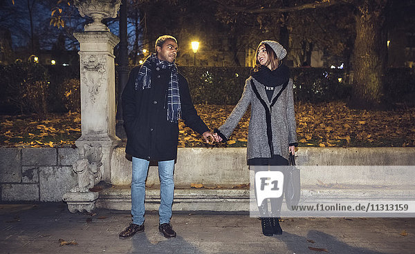 Ein glückliches junges Paar,  das sich anschaut,  während es Händchen hält.