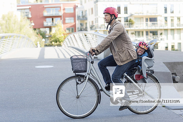 Mann fährt Fahrrad mit Sohn auf dem Rücksitz