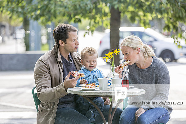 Eltern mit Sohn essen Kuchen in einem Straßencafé