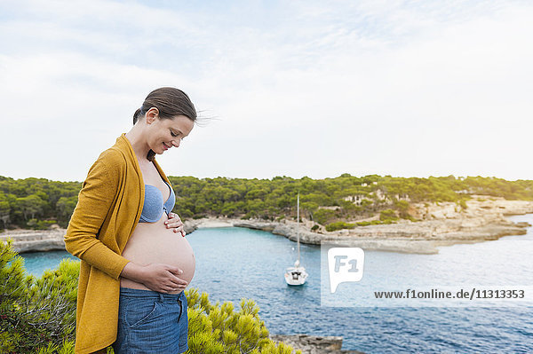 Schwangere Frau am Meer stehend