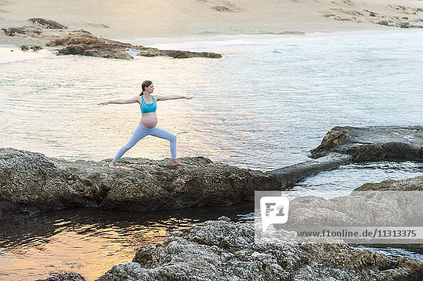 Schwangere Frau beim Yoga am Meer
