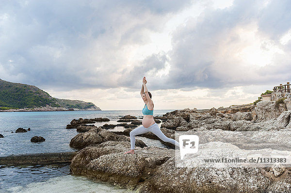 Schwangere Frau beim Yoga am Meer