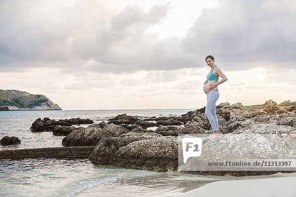Schwangere Frau am Meer stehend