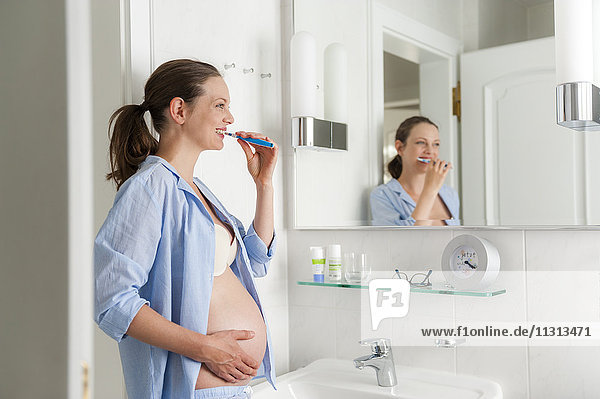 Schwangere Frau im Bad beim Zähneputzen