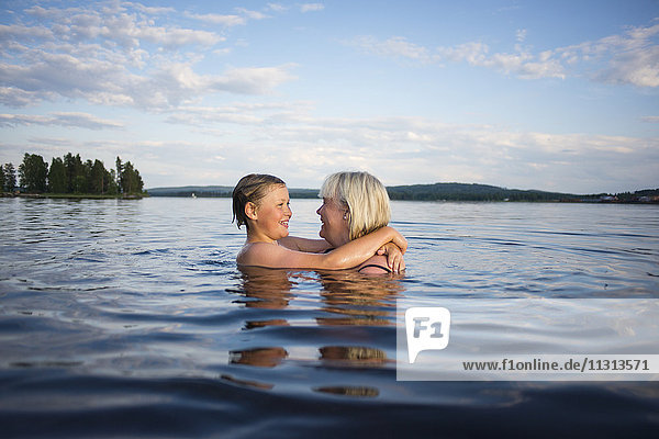 Mother and daughter swimming in lake
