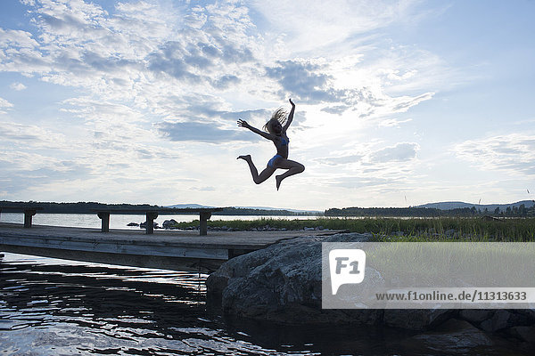 Girl jumping by lake