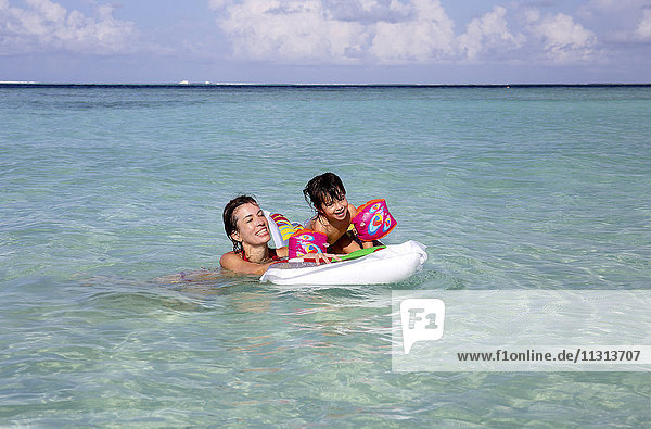Malediven  Gulhi  Mutter und Tochter beim Spielen mit einem aufblasbaren Luftbett im Flachwasser