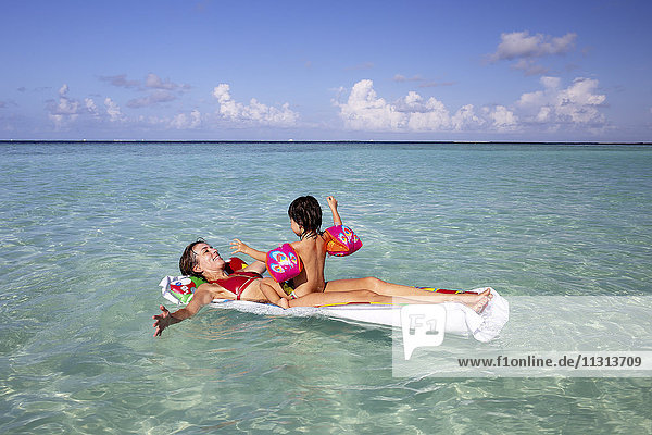 Malediven  Gulhi  Mutter und Tochter beim Spielen mit einem aufblasbaren Luftbett im Flachwasser