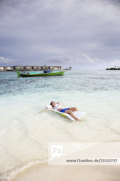Malediven  Guraidhoo  Frau auf Luftmatratze im Flachwasser schwimmend