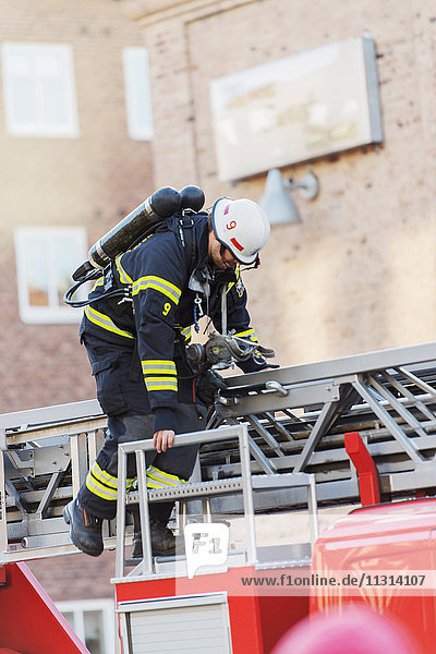 Firefighter standing on top of firetruck