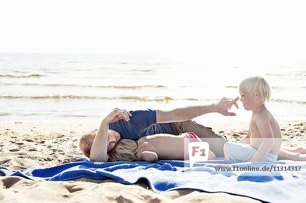 Vater spielt mit Söhnen am Strand