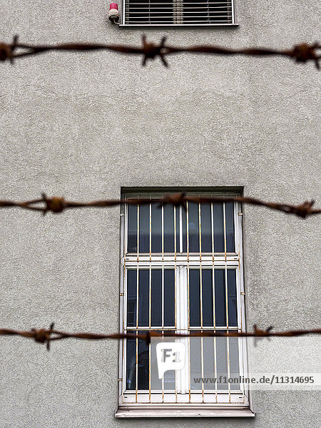 Barred window behind barbed wire