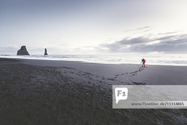 Island  Südisland  Fotograf beim Fotografieren von Vik Rock am Strand von Reynisfjara