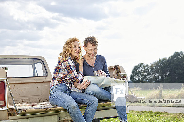 Couple sitting on pick up truck reading map