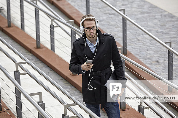 Young man with headphones and cell phone outdoors