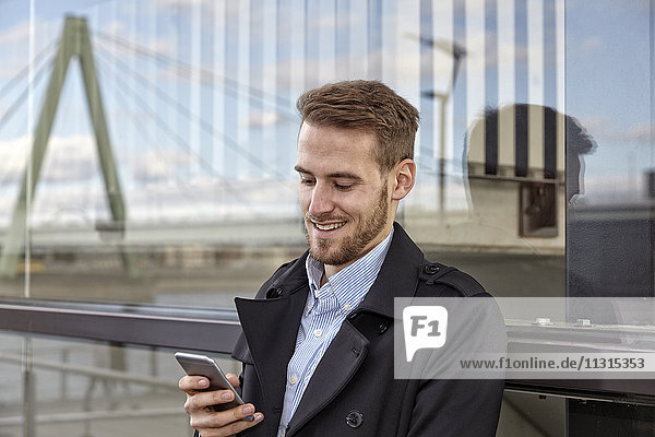 Lächelnder junger Mann auf dem Handy im Freien