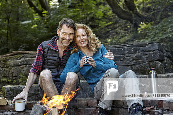 Glückliches Paar sitzt am Lagerfeuer