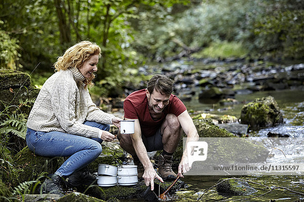 Couple washing dishes at a river