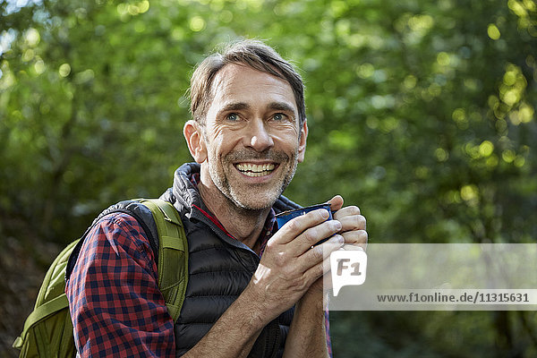 Hiker in forest holding cup of tea