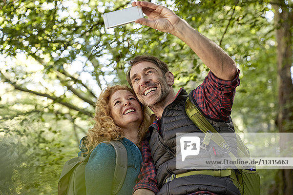 Hiking couple taking selfies with smart phone in forest