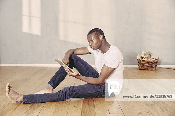 Young man sitting on floor using tablet
