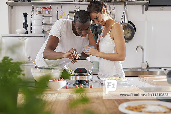 Happy young couple preparing waffles in the kitchen