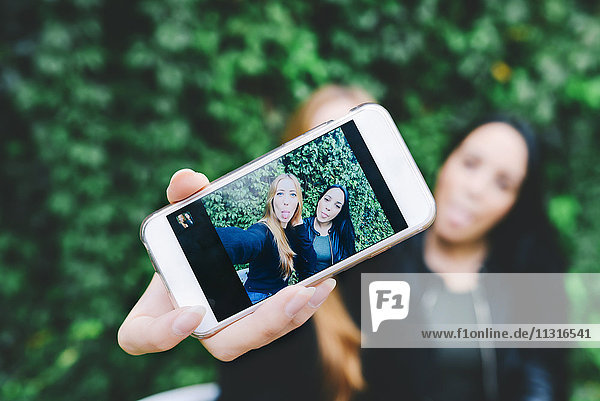 Two friends showing selfie on smart phone