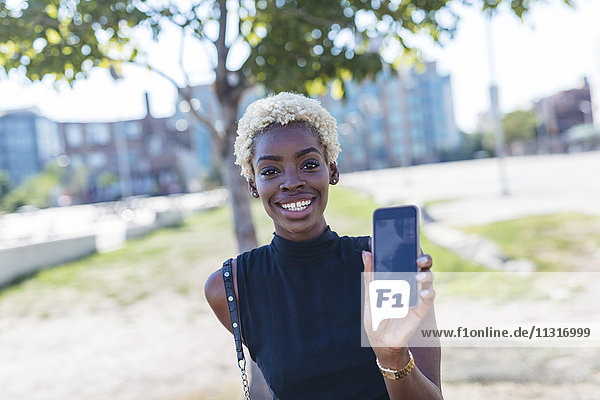 Porträt einer lächelnden jungen Frau mit ihrem Handy