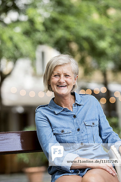 Porträt der lächelnden Seniorin auf der Bank in der Stadt