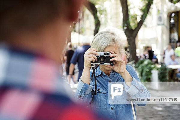 Seniorin beim Fotografieren ihres Partners mit der Kamera
