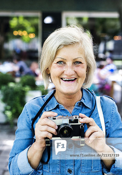 Portrait of happy senior woman with camera